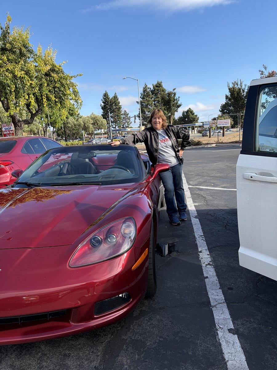 Marian standing beside her red C6 Corvette