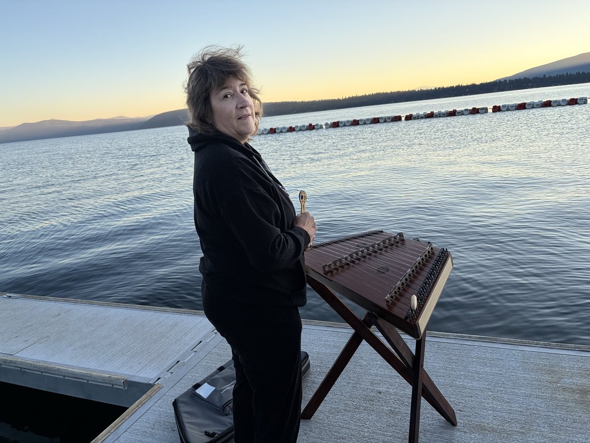 Marian playing a hammered dulcimer beside a mountain lake